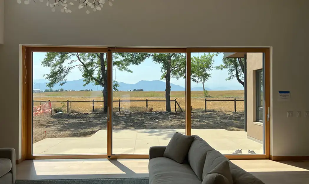 Interior living room with a large glazed opening overlooking trees and open landscape.